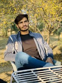 Young man looking away while siting outdoors