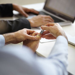 Cropped hands of woman using mobile phone on table