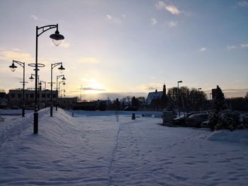 Snow covered landscape against sky during sunset