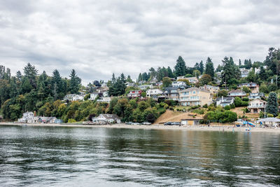 Houses by river against sky in town