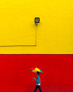 Full length of man standing against yellow wall