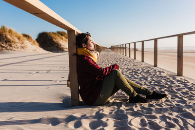 Young woman with eyes closed relaxing at beach at sunset. holidays and relaxation concept