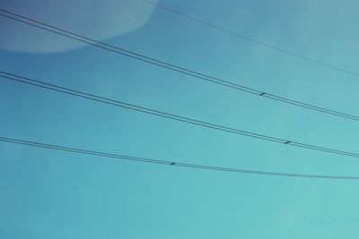 Low angle view of power cables against blue sky