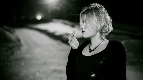 Close-up of young woman smoking cigarette at night