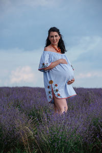 Woman standing on field against cloudy sky