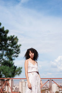 Woman with curly hair standing against sky