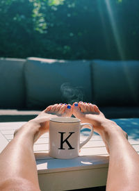 Midsection of person relaxing on swimming pool