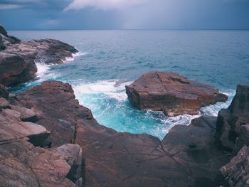 Rock formation in sea against sky