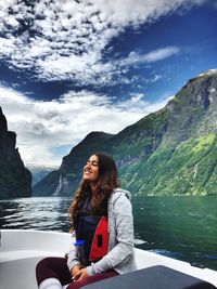 Young woman sitting on lake against mountains