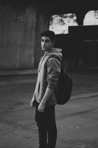 Portrait of young man standing on footpath in city