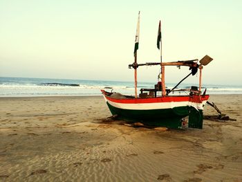 Boat on beach against clear sky during sunset