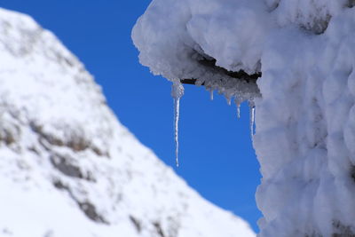 Low angle view of frozen mountain against blue sky