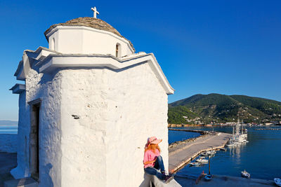 Traditional building by sea against clear blue sky