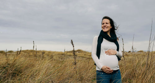Portrait of smiling young woman standing on field