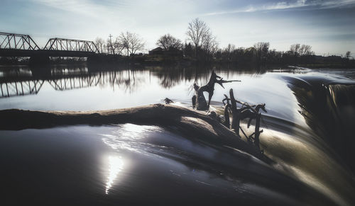 Silhouette trees by lake against sky