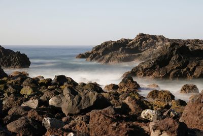 Scenic view of rocks in sea against clear sky