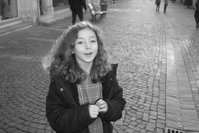 Portrait of a smiling girl on footpath in city