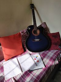 Electric guitar on bed against wall at home