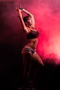Woman exercising with dumbbell in artificial fog