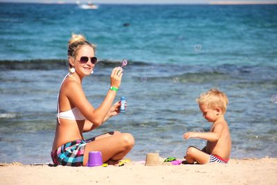 Happy friends sitting on shore at beach