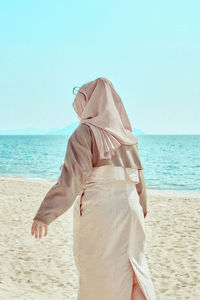 Rear view of woman standing at beach