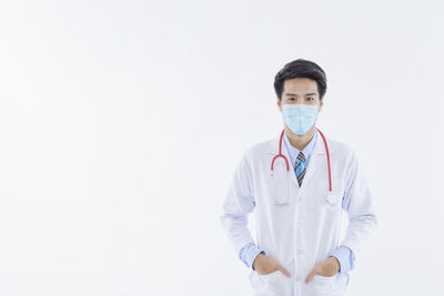 Portrait of young man standing against white background