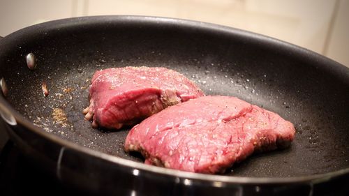 Close-up of steak cooking on frying pan at home