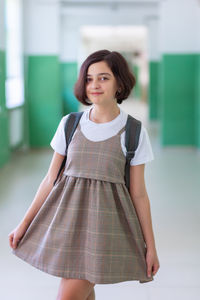 Portrait of young woman standing against wall