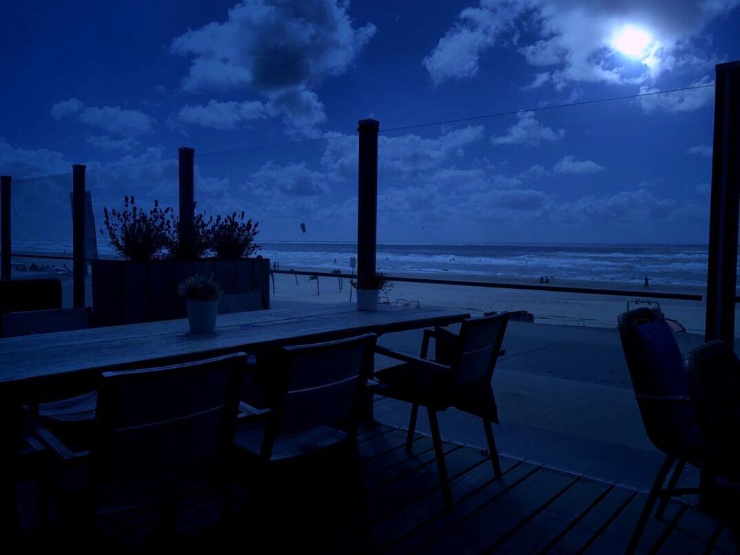 CHAIRS AND TABLE AT SEA AGAINST SKY