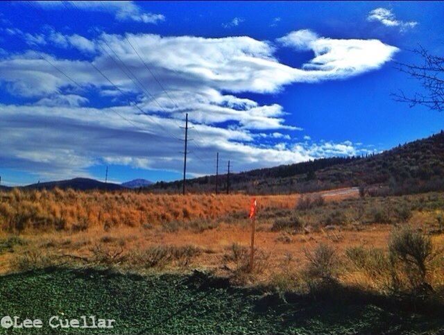 sky, landscape, tranquility, tranquil scene, cloud - sky, scenics, field, nature, grass, cloud, beauty in nature, electricity pylon, blue, non-urban scene, mountain, fuel and power generation, plant, power line, countryside, cloudy