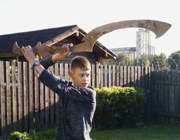 Teenage boy holding equipment while standing in yard