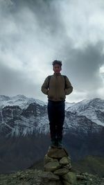 Man standing on rock against sky