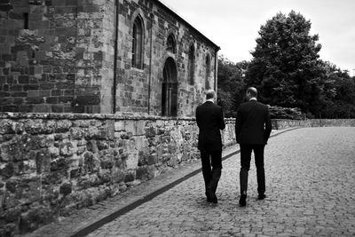 Rear view of businessmen walking down cobblestone street