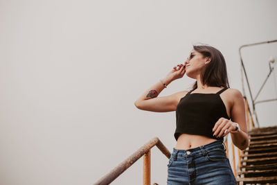 Young woman standing against clear sky