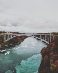 Arch bridge over river against sky