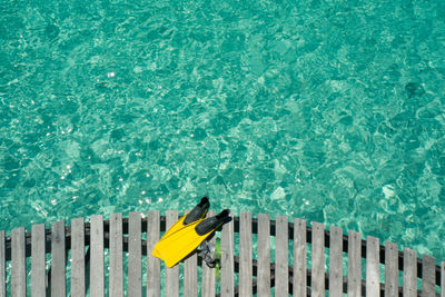 High angle view of snorkeling flippers and swimming goggles on pier over sea