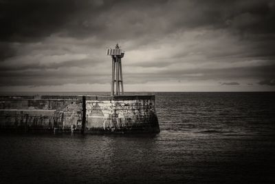 Lighthouse by sea against sky