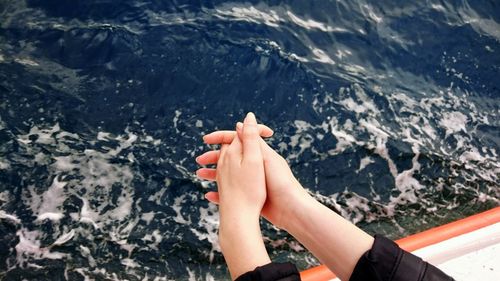 Cropped hand of woman on boat against sea