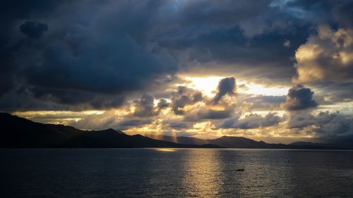 Scenic view of sea against dramatic sky during sunset