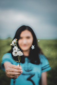 Woman holding dandelion flower against sky