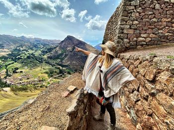 Full length of woman standing on wall against mountain