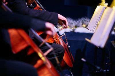 Midsection of musicians playing cello on stage