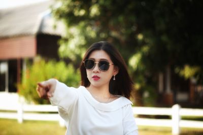 Woman wearing sunglasses gesturing outdoors