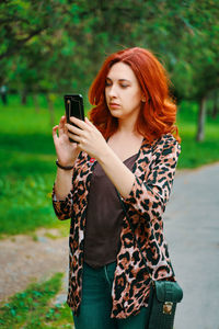 Young woman using mobile phone while standing on camera