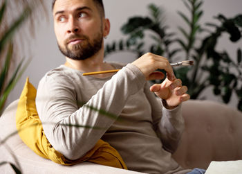 The artist is sitting on the sofa and holding a brush in his hands, learning process, lifestyle