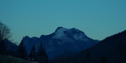 Low angle view of snowcapped mountains against clear blue sky