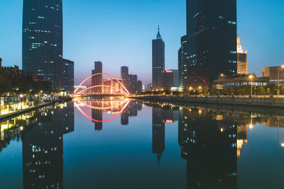 Reflection of illuminated buildings in city against sky