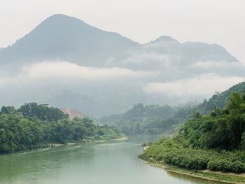 Scenic view of river by mountains against sky