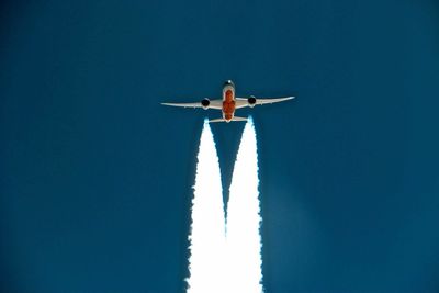 Low angle view of men airplane against clear blue sky