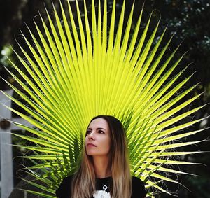 Thoughtful beautiful young woman standing against palm tree